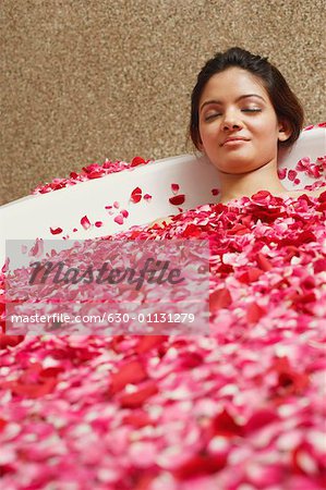 Young woman reclining in a bathtub full of rose petals