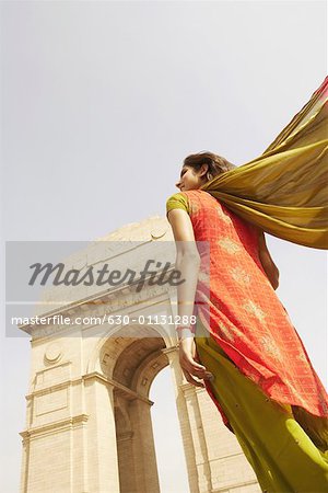 Low angle view of a young woman standing in front of a monument, India Gate, New Delhi, India