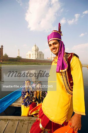 Porträt eines jungen Mannes lächelnd mit zwei jungen Frauen sitzen in einem Boot im Hintergrund, Taj Mahal Agra, Uttar Pradesh, Indien