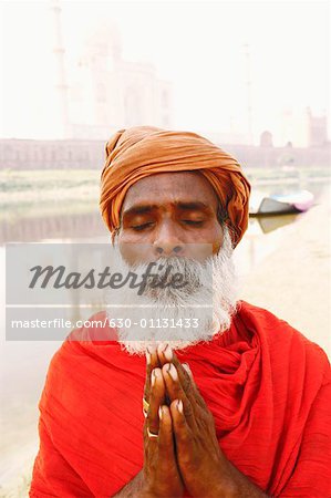 Close-up of a priest standing in a prayer position on the riverbank, Taj Mahal, Agra, Uttar Pradesh, India