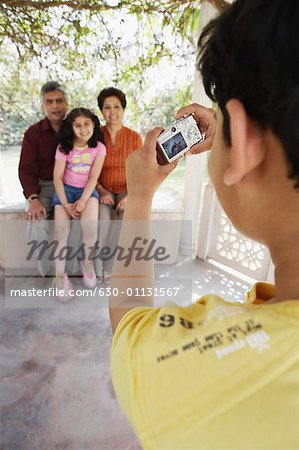 Rear view of a boy taking a picture of his grandparents and his sister