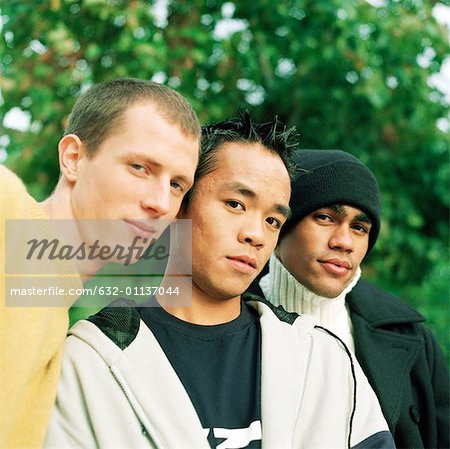 Three young men looking into camera, low angle view