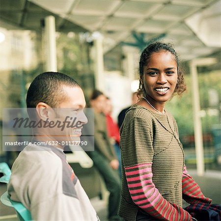 Jeune femme et jeune homme assis ensemble à la gare routière