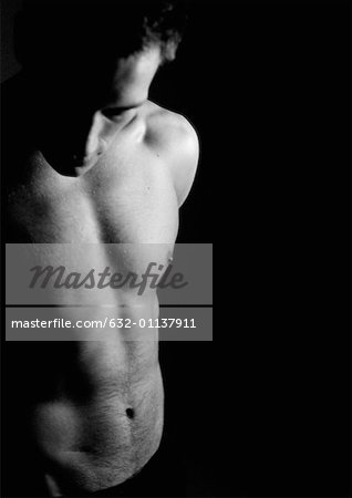 Barechested man looking down, partial view, waist up, black and white.