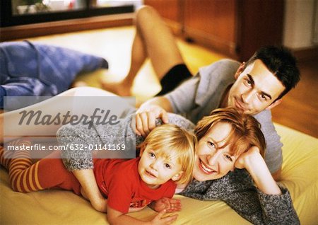 Couple and child lying on bed, portrait