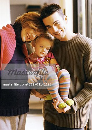 Couple holding child, smiling, portrait