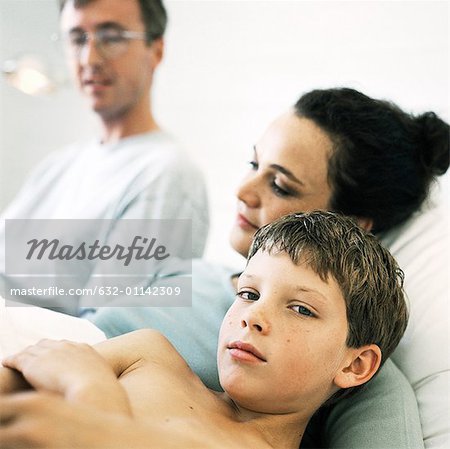 Child lying in bed with parents, portrait