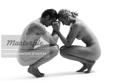 Nu homme et femme accroupie, front touchant, mains jointes, b&w