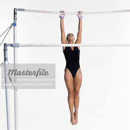 Young female gymnast hanging on uneven bars