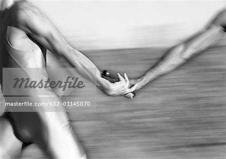 Male athletes passing relay baton, close-up, b&w