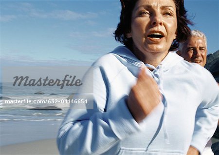 Mature couple running on beach, close-up