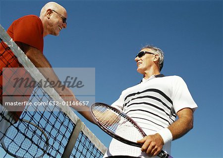 Deux hommes mûrs, serrant la main sur le net, tennis à faible angle vue