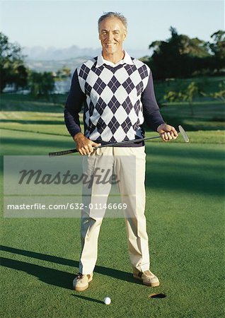 Homme d'âge mûr tenant golf club suivant pour trou, portrait