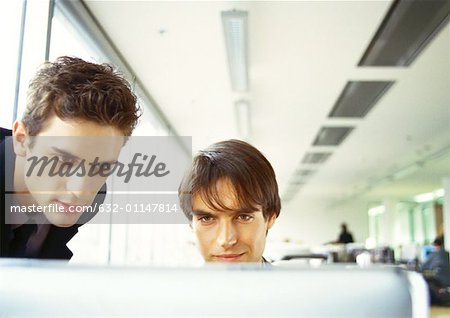 Two men's heads, edge of computer screen in foreground