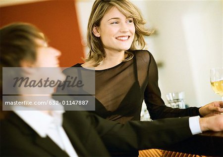 Young man and woman at bar, smiling