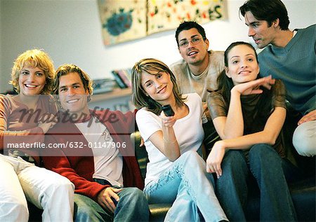 People sitting together on couch, one woman holding remote