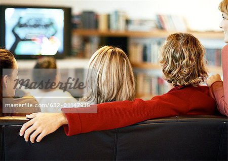 People sitting on couch watching TV, rear view