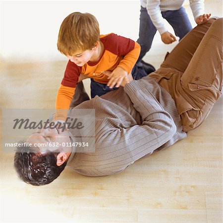 Enfants qui jouent avec le père sur le plancher