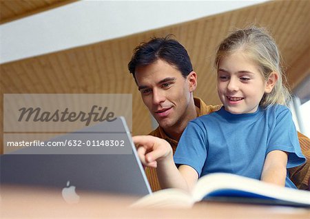 Père et fille travaillant ensemble sur ordinateur.