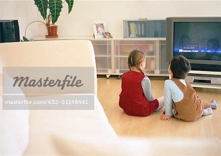 Little Boy und Girl zusammensitzen auf Parkett Boden betrachten tv, Rückansicht