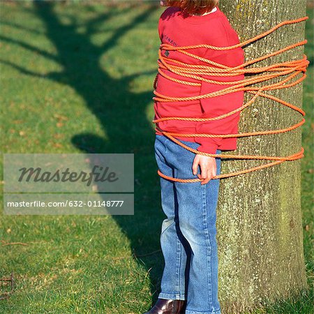 Child tied to tree, cropped