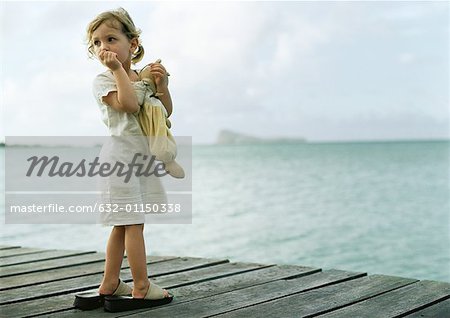 Little girl standing on dock, sucking thumb and looking over shoulder