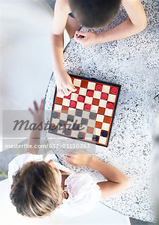 Two children playing checkers, view from directly above