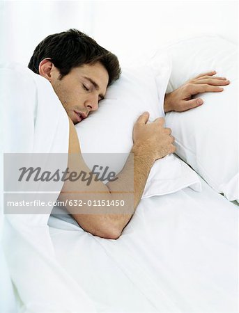 Homme couché sur le ventre sur le lit avec les yeux fermés