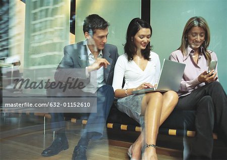 Geschäftsleute auf Bank, mit Laptop und Handy