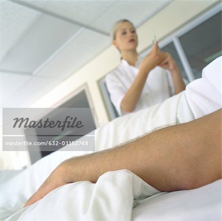 Infirmière, debout sur le patient dans son lit