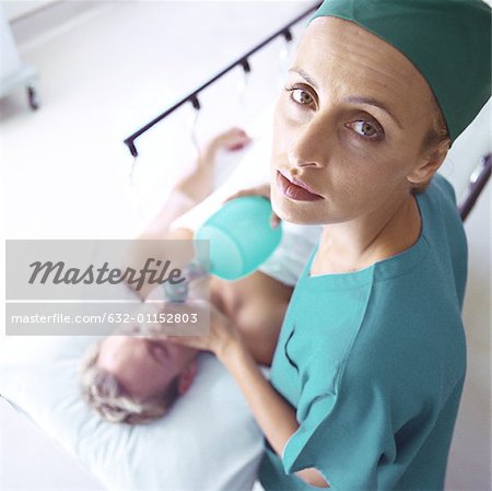 Female doctor holding oxygen mask over patient's face, high angle view