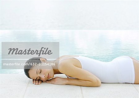 Woman napping on ground at edge of water