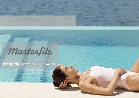 Femme couchée au bord de la piscine au soleil