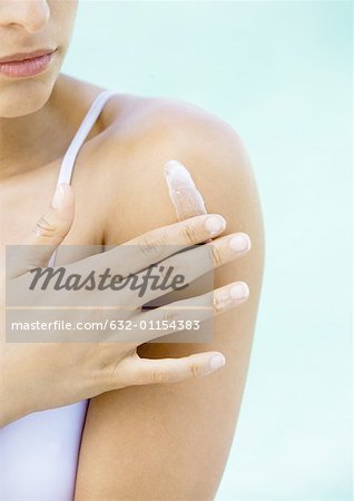 Woman applying cream to shoulder