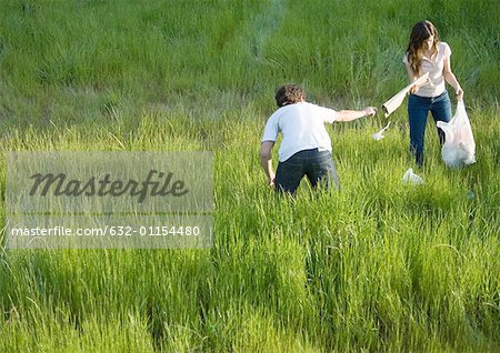 Young couple picking up litter in field