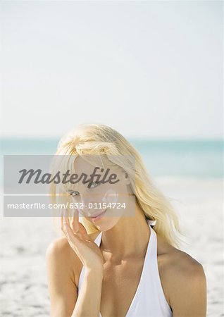 Woman applying sunscreen to face on beach