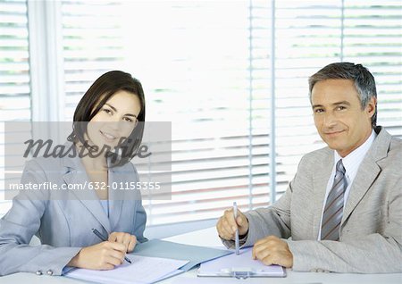 Geschäftsleute Signieren von Dokumenten, lächelnd in die Kamera