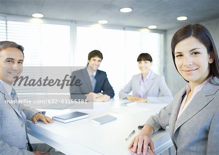 Executives sitting around table, smiling at camera