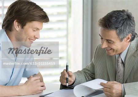 Young man with mature business man, looking at document