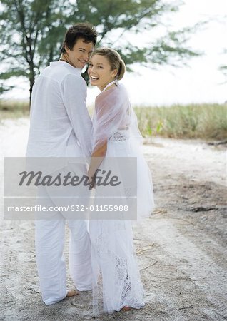 Bride and groom walking on sand