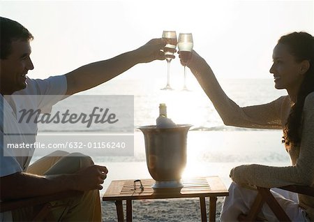 Young couple clinking champagne glasses on beach