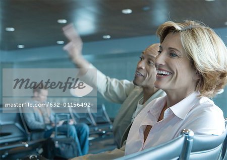 Man and woman sitting in airport lounge, laughing