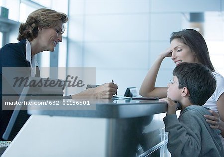 Woman and son standing at check-in counter in airport