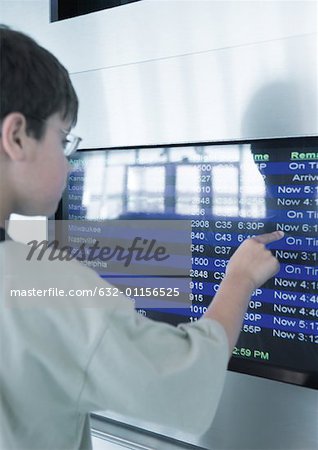 Boy touching departure board screen