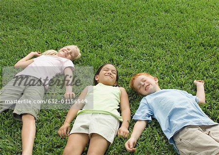 Three children lying in grass