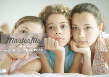 Preteen girls leaning on elbows, looking out of frame