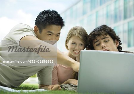 Three college students using laptop outdoors