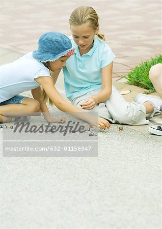 Suburban children playing marbles on asphalt