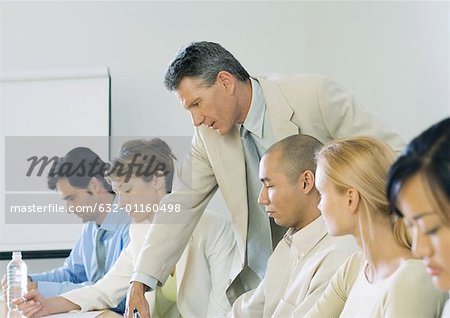 Businessman leaning over colleague's shoulder during meeting