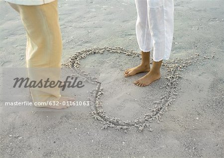 Frau stehend im inneren Herzen gezeichnet am Strand, mit Blick auf Mann, niedrige Abschnitt